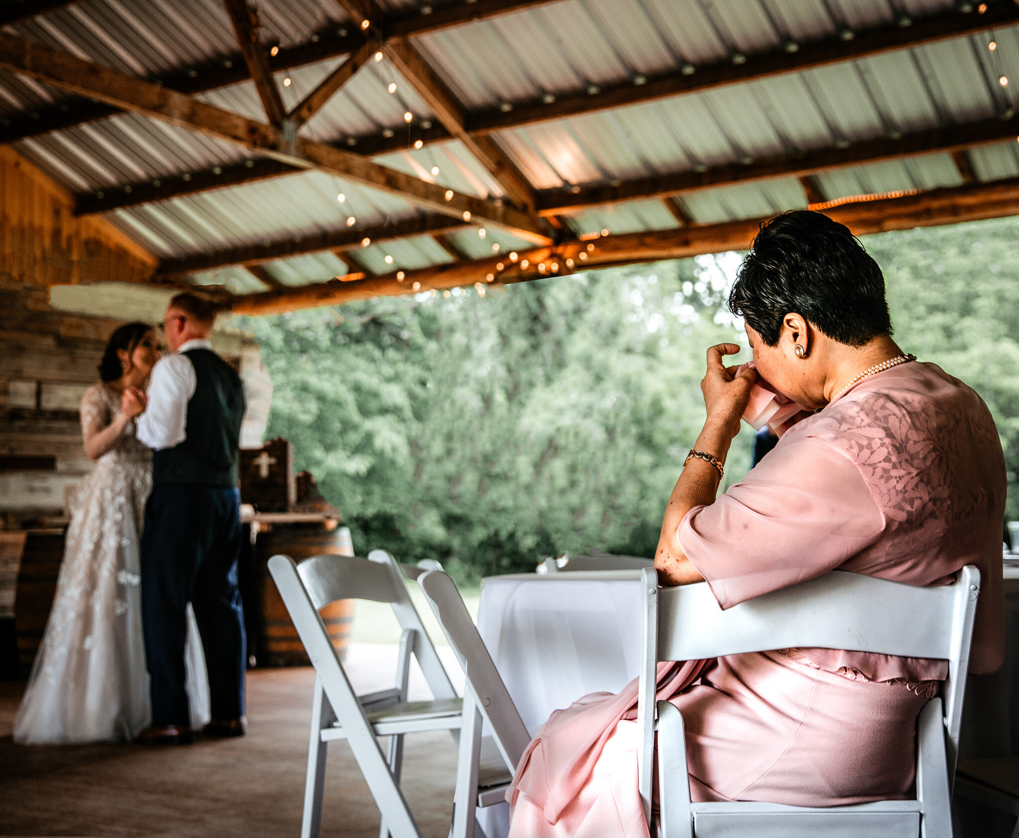 Mother wiping tears watching her daughter's wedding first dance